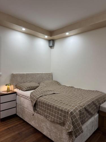 a bedroom with a bed and a white wall at Apartman Trg in Šabac