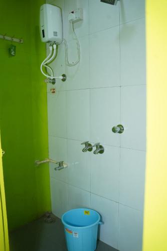 a bathroom with a bucket and a phone on the wall at Dr Vijeta's Wellness Retreat in Alībāg