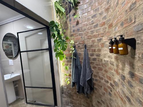 a bathroom with a mirror and a brick wall at 16 st Johns - Studio 2 in Port Shepstone