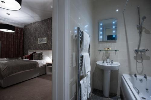 a bathroom with a bed and a tub and a sink at Parkwood Hotel in Stockton-on-Tees