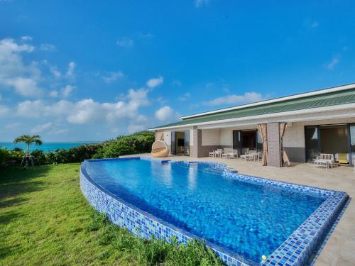 a swimming pool in front of a house at Miyakojima Kurima Resort Seawood Hotel in Miyako-jima