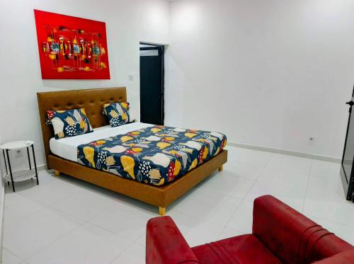a bedroom with a bed and a red couch at Izuba APPART' HÔTEL in Ngaparou