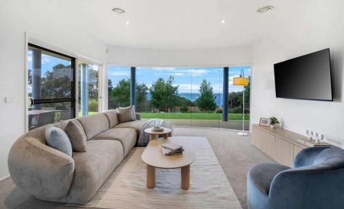 a living room with a large couch and a tv at Ultimate Ocean Views - Pet Friendly in Bellbrae