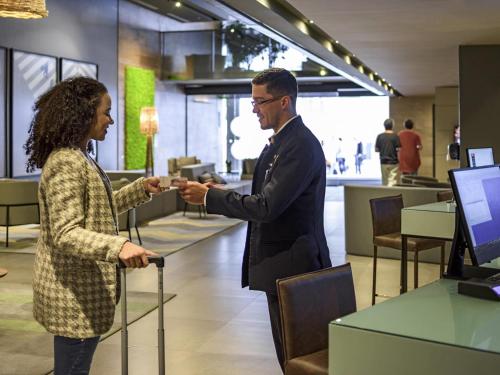 a man and a woman shaking hands in a store at Novotel Curitiba Batel in Curitiba