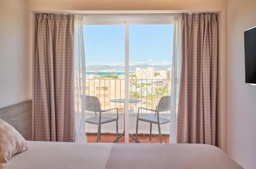 a bedroom with a bed and a balcony with chairs at tent Playa de Palma in Playa de Palma