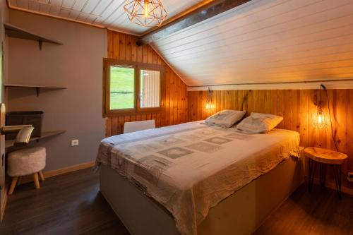 a bedroom with a large bed in a wooden room at Grange des 2 Cols - Jacuzzi - Jardin in Campan