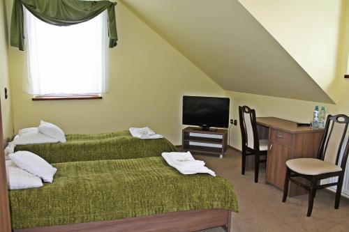 Zimmer mit 2 Betten, einem Schreibtisch und einem TV in der Unterkunft Pod Strzechą in Malawa