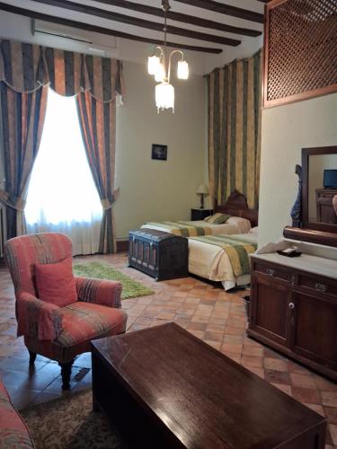 a bedroom with two beds and a chair and a table at Hotel Ordóñez Sandoval in Úbeda