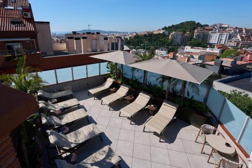 a patio with white chairs and umbrellas on a building at Catalonia Park Güell in Barcelona