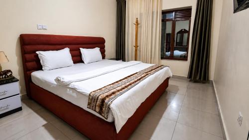 a bedroom with a large bed with a red headboard at Bati Valley Guest House in Kigali