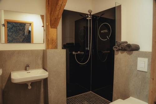 a bathroom with a shower with a sink and a toilet at Motel Q Kornspeicher in Neuruppin