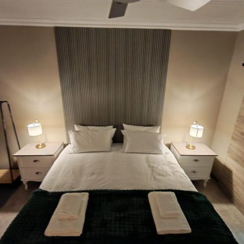 a bedroom with a white bed with two nightstands and two lamps at L'Mida in Klerksdorp