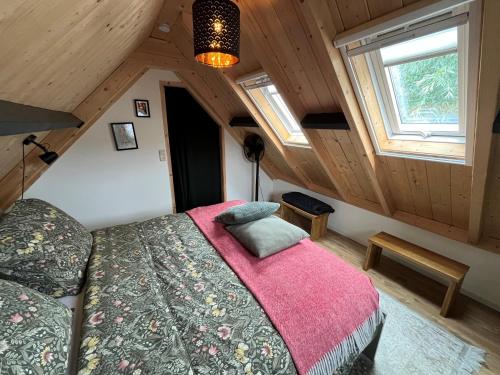 a bedroom with a bed with a pink blanket at Gastenverblijf Boven De S l a g e r i j in Schijndel