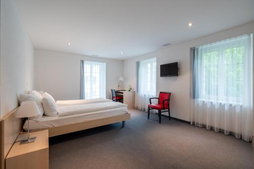a bedroom with a bed and a red chair at Hotel Ochsen - Self Check-in in Uster
