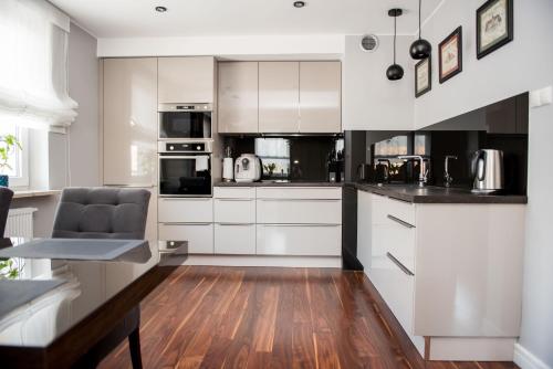 cocina con armarios blancos y suelo de madera en Apartament przy S3, en Nowa Sól