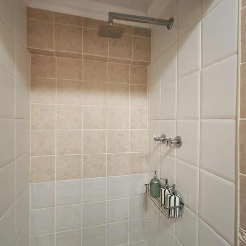 a bathroom with a shower with a tiled wall at L'Mida in Klerksdorp