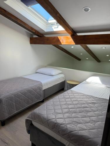 two beds in a bedroom with a skylight at Villa Adria in Novalja