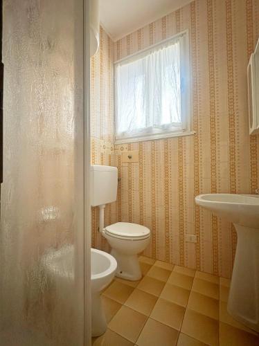 a bathroom with a toilet and a sink and a window at Residence MARE App Alga 24 in Lido delle Nazioni