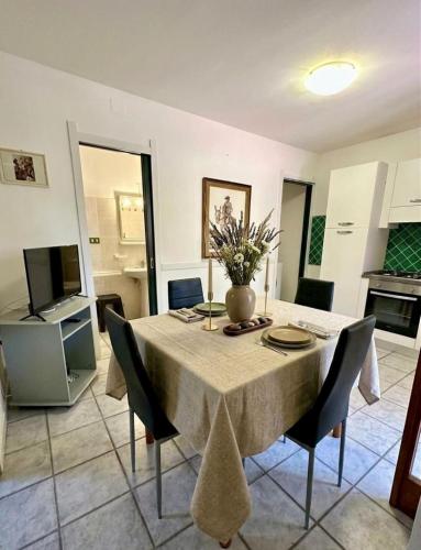 a dining room table with a vase of flowers on it at Le Case dei Ginepri in Marina di Sorso