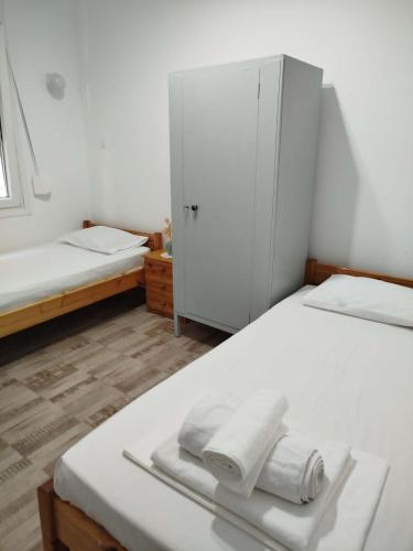 a white bedroom with two beds and a cabinet at Δωμάτια Σοφία in Agios Kirykos