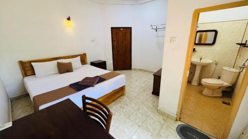 a bedroom with a bed and a bathroom with a sink at Gamagedara Resort in Dambulla