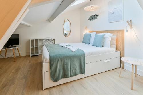 a bedroom with a white bed and a tv at La Cabane chic des Embruns in Cabourg