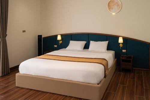 a bedroom with a large bed with a blue headboard at SOLANA VILLA Cửa Lò - Biệt thự nghỉ dưỡng cao cấp tiêu chuẩn 5 sao in Cửa Lô