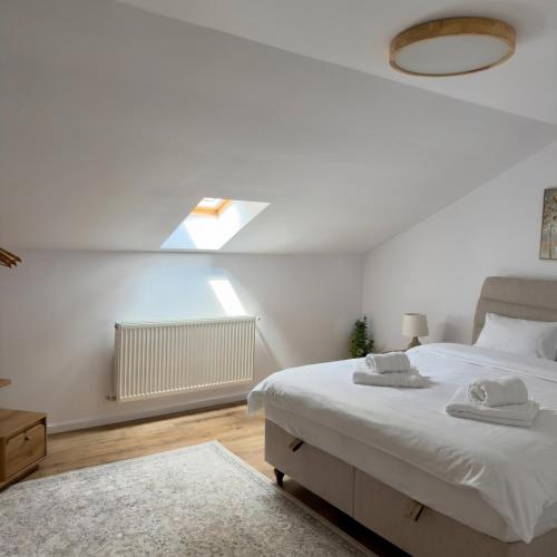 ein weißes Schlafzimmer mit einem Bett und einem Fenster in der Unterkunft Ponti's Villa in Buşteni