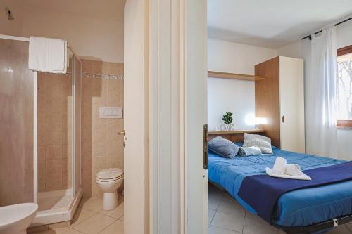 a bedroom with a bed and a shower and a toilet at Pineta Azzurra in Marina di Grosseto