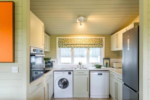 a kitchen with a washing machine and a window at The Paddock Lodge in Withcote