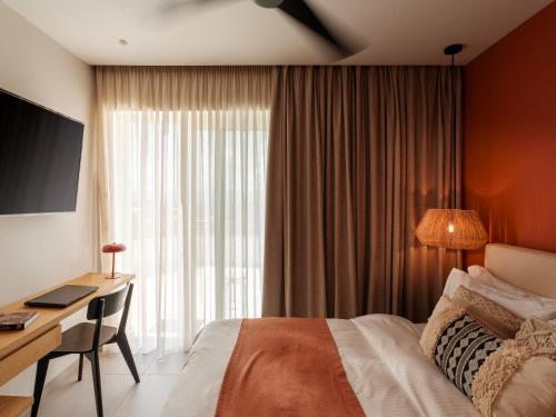 a hotel room with a bed and a desk and a window at Deos- Luxury Apartment in Agrinio in Agrinio