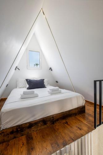 a bedroom with a white bed with a wooden floor at Danae's A-Frame Nest in Daratso