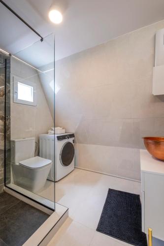 a bathroom with a toilet and a washing machine at Danae's A-Frame Nest in Daratso