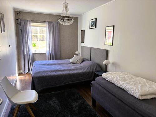 a bedroom with two beds and a chair in it at Ängshöjd in Sandhem