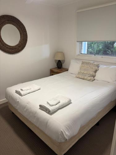 a bedroom with a large white bed with towels on it at Bella Vita Beach House in Robe