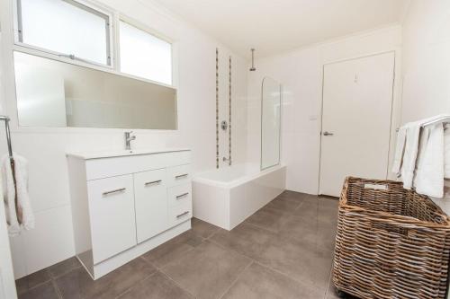 a white bathroom with a tub and a sink and a shower at Bella Vita Beach House in Robe
