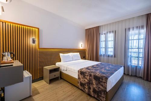 ein Hotelzimmer mit einem Bett und zwei Fenstern in der Unterkunft Costa Bitezhan Beach Hotel in Bitez