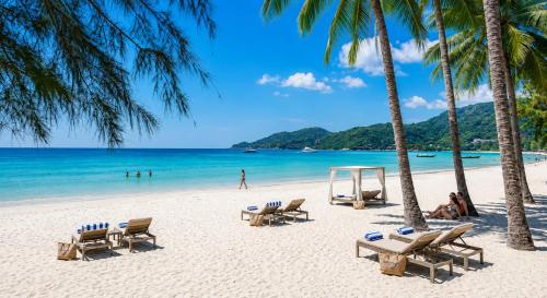 a beach with chairs and palm trees and the ocean at The Taksim Bangla Beach Hotel in Patong Beach
