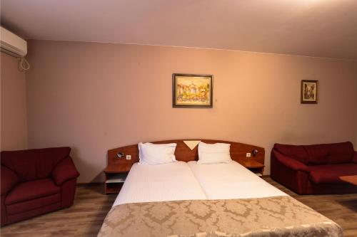 a bedroom with a bed and two red chairs at Philippopolis Hotel in Plovdiv