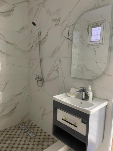 a white bathroom with a sink and a mirror at Nesma Douaouda in Douaouda