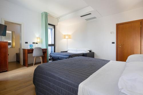 a hotel room with two beds and a desk at Hotel Sirena & Cucina in Cesenatico