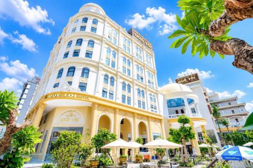 a building in a city with palm trees and umbrellas at Quê Tôi Hotel in Soc Trang