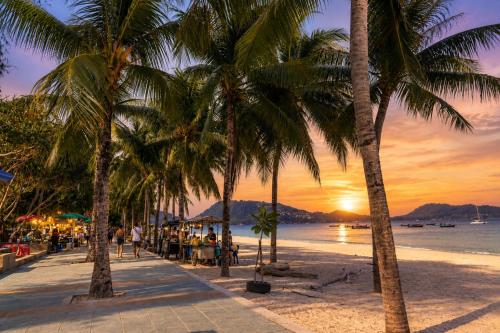 a group of palm trees on a beach at sunset at The Taksim Bangla Beach Hotel in Patong Beach