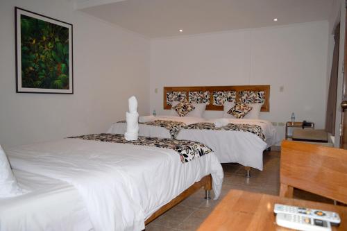 a bedroom with two beds with white sheets and a table at Hotel Jungle House in Iquitos