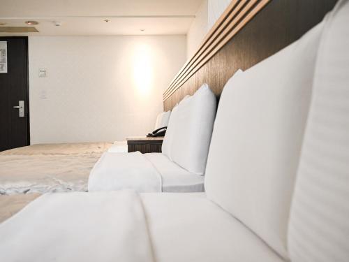 a hotel room with two beds with white pillows at Guide Hotel Taoyuan Fuxing in Taoyuan
