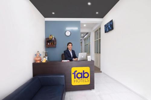 a woman sitting at a reception desk with a laptop at FabHotel Samarth Residency By the Arrow in New Delhi