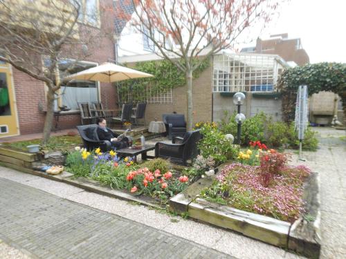 a man sitting in a chair in a garden with flowers at Pension de Zeeschelp in Domburg