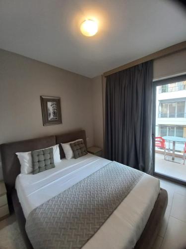 a bedroom with a large bed and a large window at Pool View Private Apartment in Vlorë
