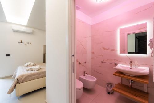a pink bathroom with a sink and a bed at Tortugas B&B in Giarre