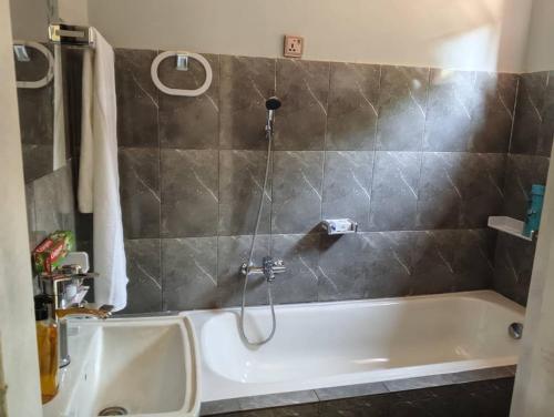 a bathroom with a bath tub with a shower at Maisonnette KF Golf-Self Catering Apartments in Lubumbashi